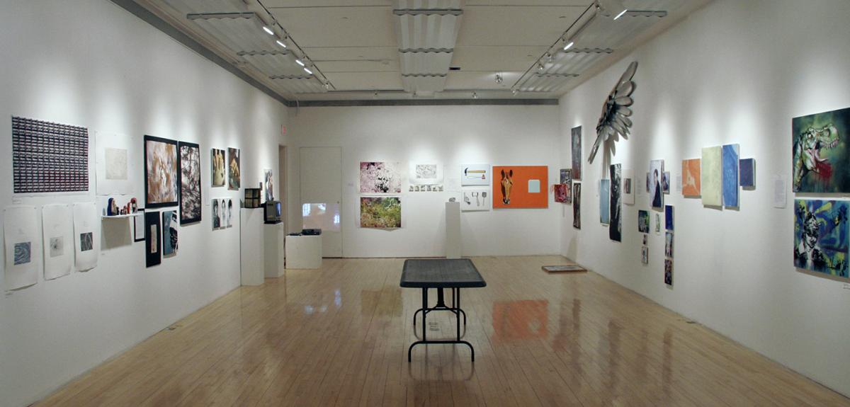 view of a gallery with white walls and many pieces hung on the walls