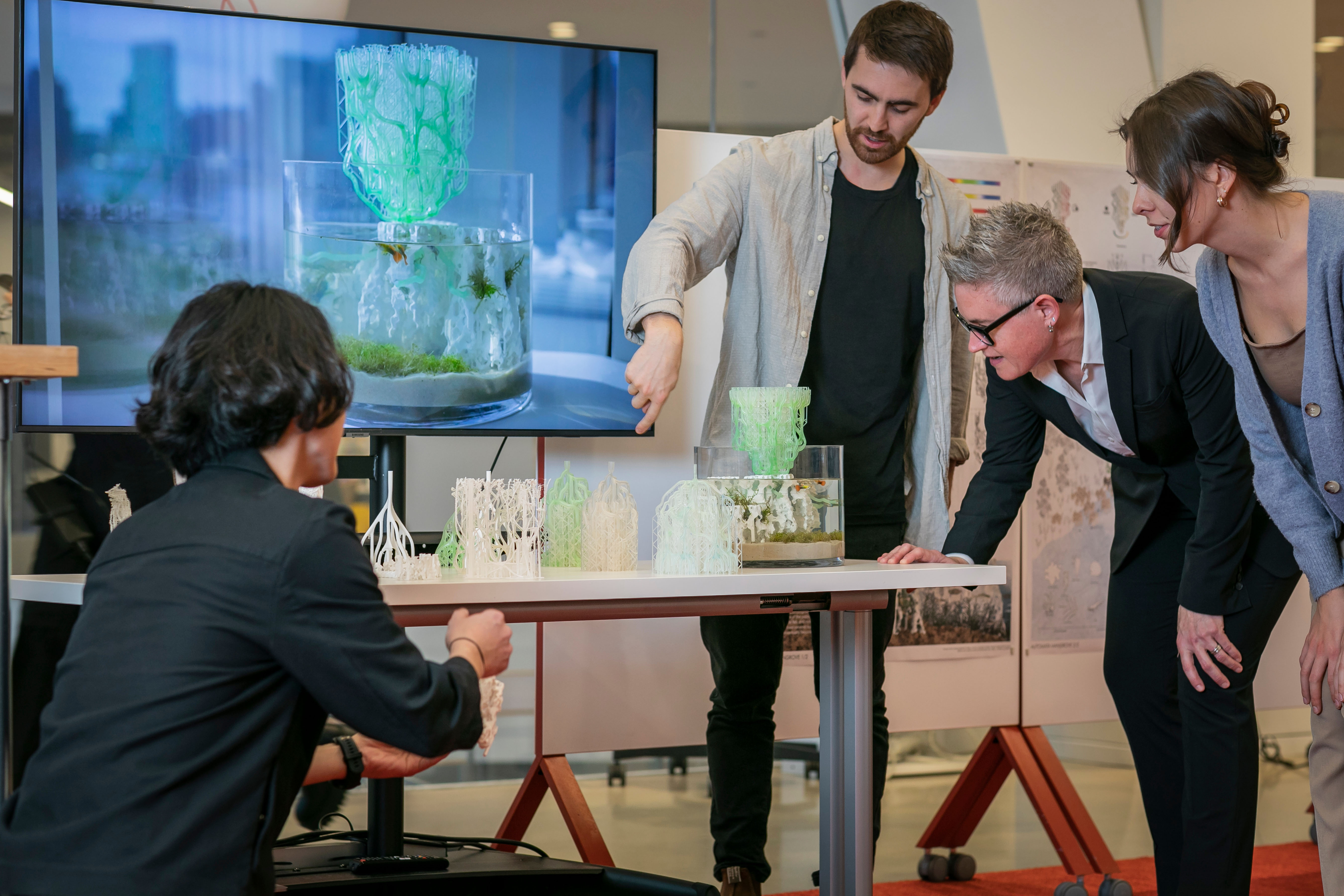 People looking at a model sitting on a table.