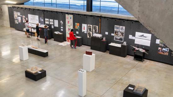 people standing and observing works of art pinned on a wall.