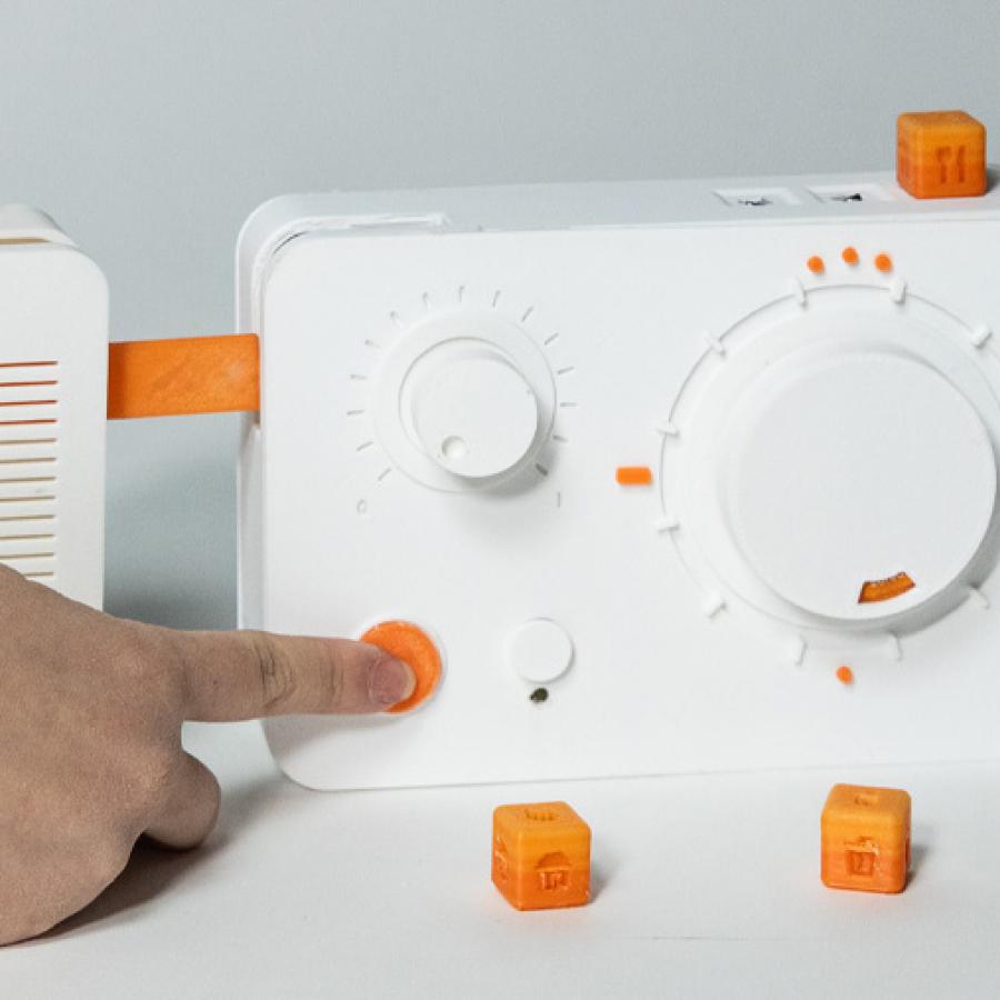 A hand operating a rectangular device with buttons, rotationg knobs, and small cubic attachable pieces.